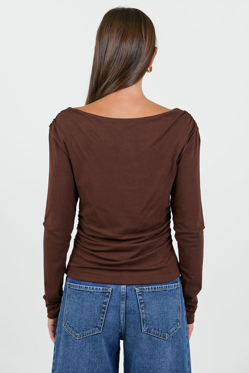 Woman wearing a chocolate brown long sleeve top and blue jeans