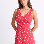model wearing a red white polka dot mini dress with a V neck and button front