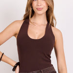 A woman modeling a dark brown ribbed tank top and a dark brown denim mini skirt with a matching belt, paired with black flip-flop sandals, against a plain white studio background.