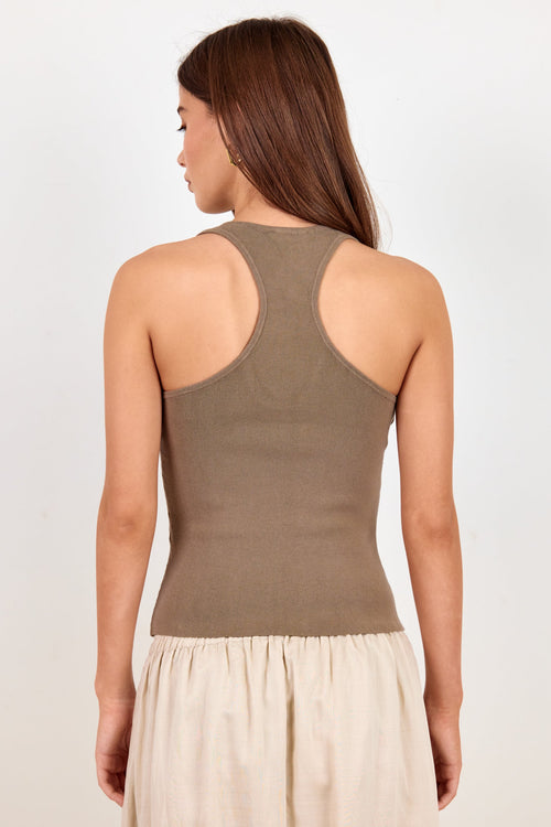 A woman shown from the back wearing a sleeveless ribbed knit tank top in taupe brown and a light beige skirt, against a plain light gray studio background.