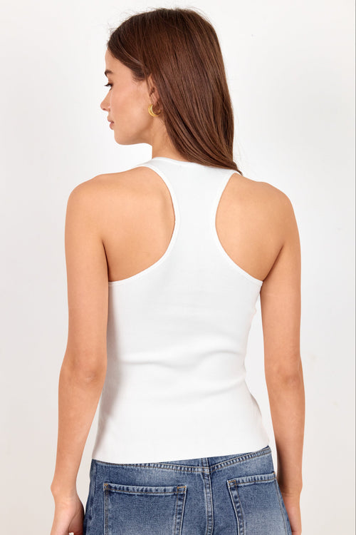 A woman shown from the back wearing a fitted white racerback tank top and blue jeans against a plain light background.