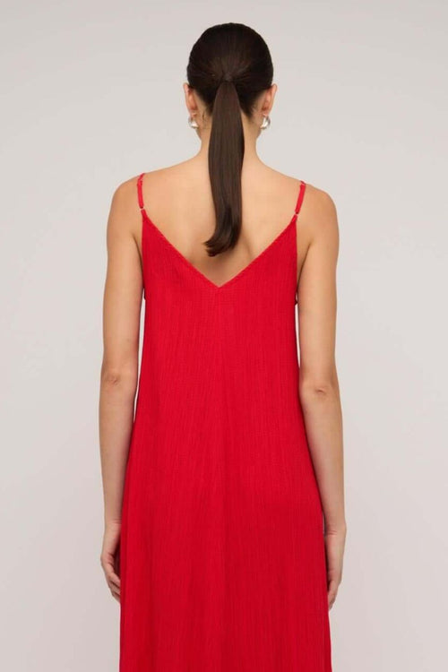 Bright red textured maxi dress with thin spaghetti straps and a deep V-neckline, styled in a relaxed fit, worn by a model against a neutral background.