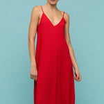 Bright red textured maxi dress with thin spaghetti straps and a deep V-neckline, styled in a relaxed fit, worn by a model against a neutral background.