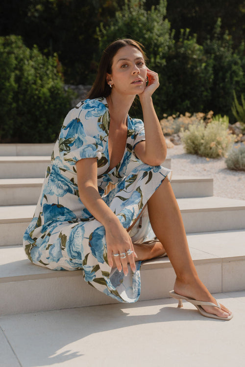 model wearing a blue floral long dress in front of a pool