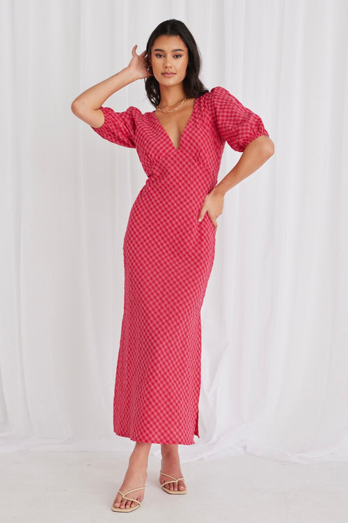 model wears a long gingham pink dress and heels