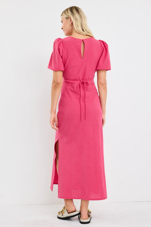 Woman wearing a pink dress with puff sleeves on a white background