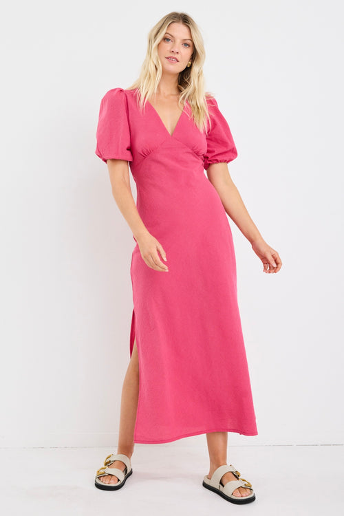 Woman wearing a pink dress with puff sleeves on a white background