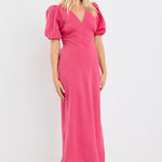 Woman wearing a pink dress with puff sleeves against a white background