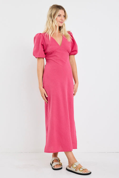 Woman wearing a pink dress with puff sleeves against a white background