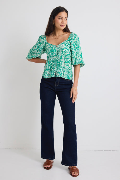 model wears green floral puff sleeve top and blue jeans