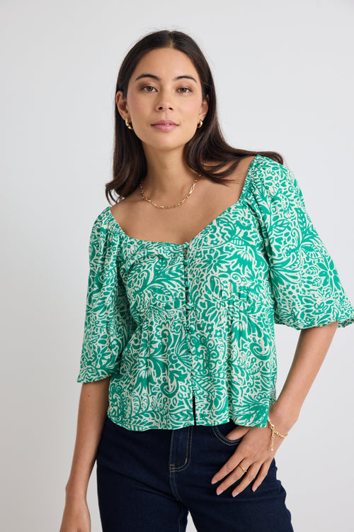 model wears green floral puff sleeve top and blue jeans