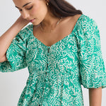 model wears a green floral blouse 