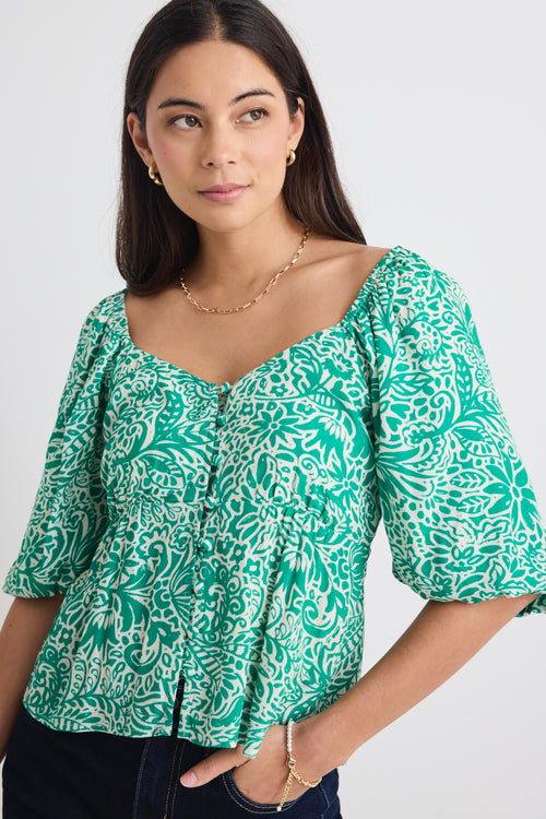 model wears a green floral blouse 