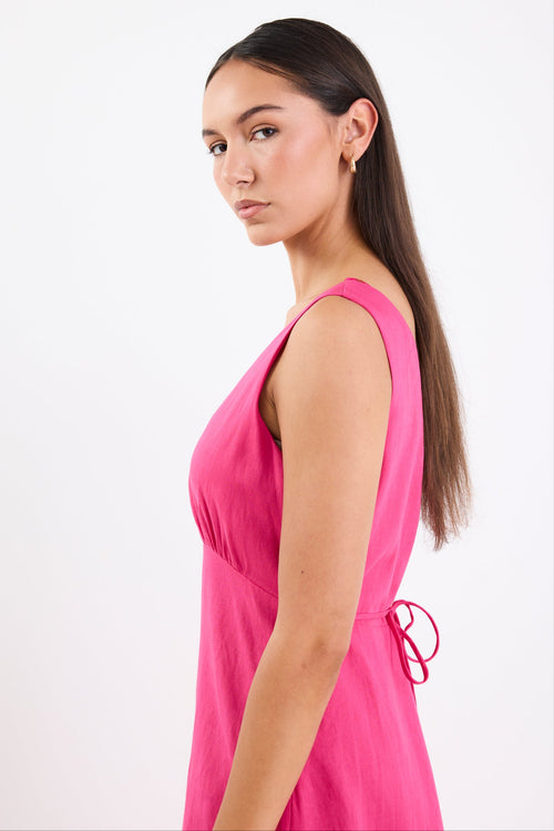 Woman wearing a bright hot pink sleeveless midi dress with a V-neckline, bias-cut silhouette, and soft flare hem.