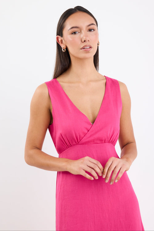 Woman wearing a bright hot pink sleeveless midi dress with a V-neckline, bias-cut silhouette, and soft flare hem.
