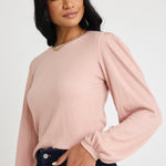 Model wears a blush pink top with jeas