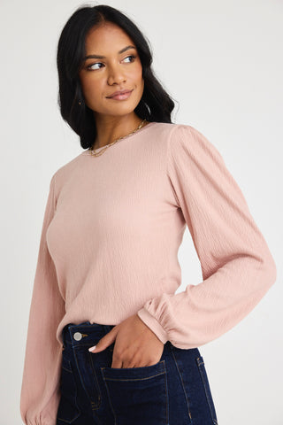 Model wears a blush pink top with jeas