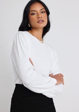 Models wears a white long sleeve top with black skirt 