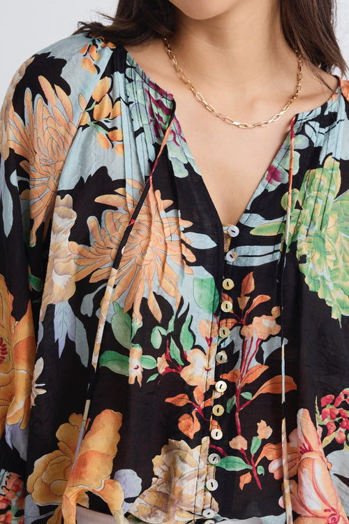 model wears a black tropical print blouse