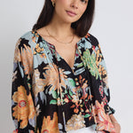 model wears a black tropical print blouse