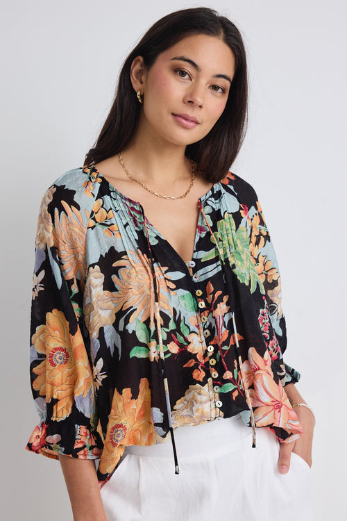 model wears a black tropical print blouse