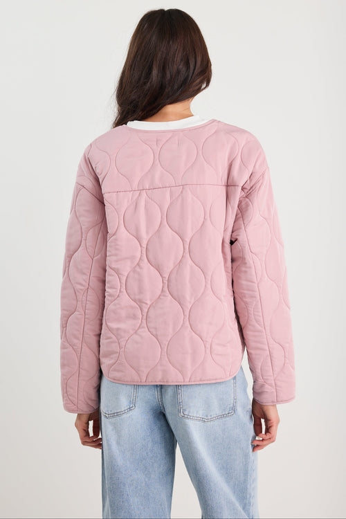 Woman wearing a pink quilted jacket and blue jeans