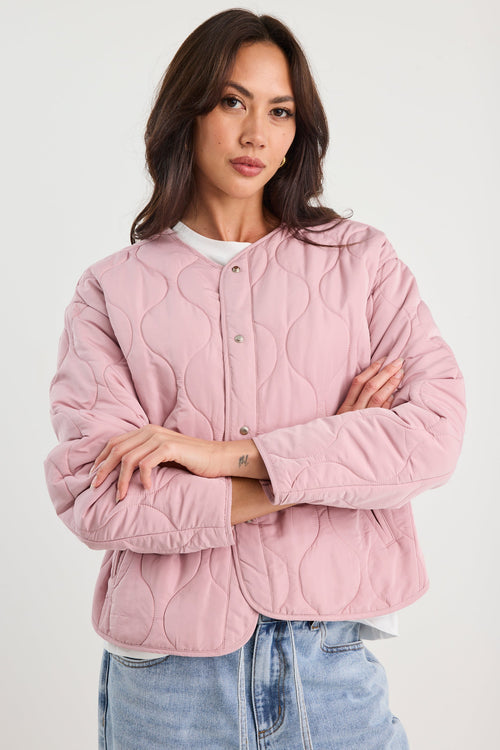 Woman wearing a pink quilted jacket and blue jeans