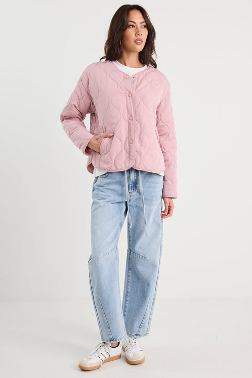 Woman wearing a pink quilted jacket and blue jeans