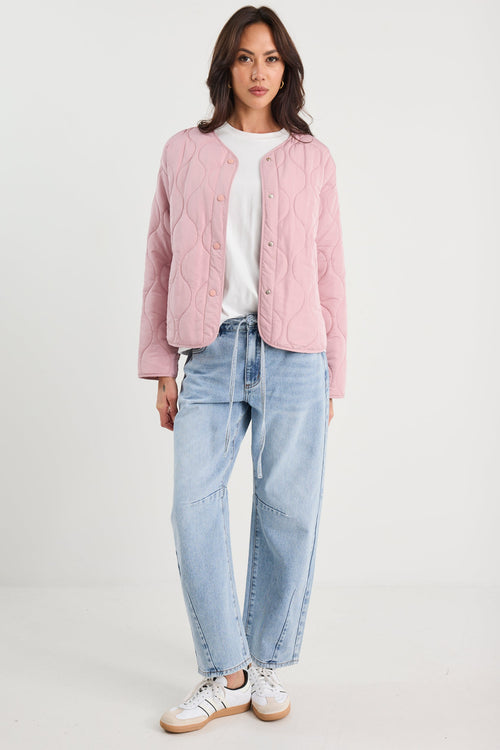 Woman wearing a pink quilted jacket and blue jeans