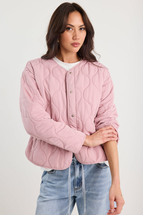 Woman wearing a pink quilted jacket and blue jeans