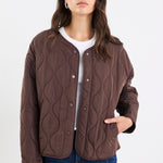 Woman wearing a brown quilted jacket on a white background