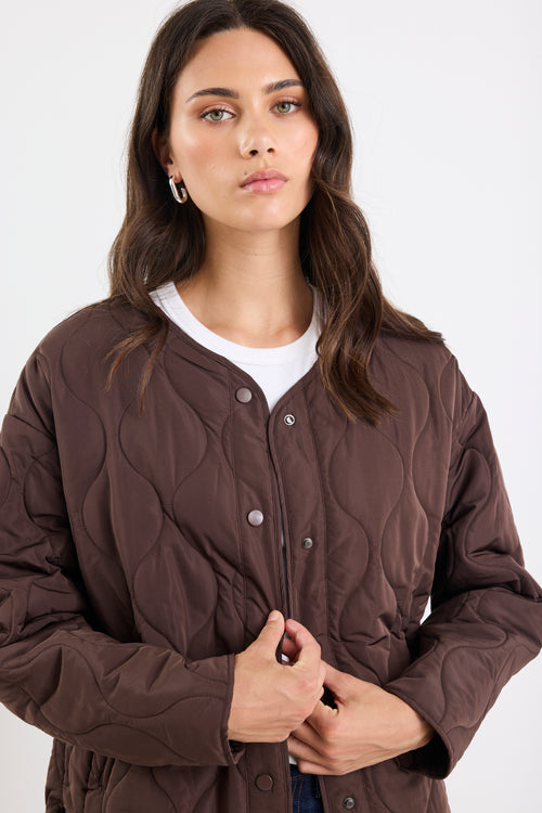 Woman wearing a brown quilted jacket on a white background