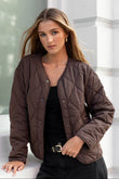 Woman wearing a brown quilted jacket in a bright room