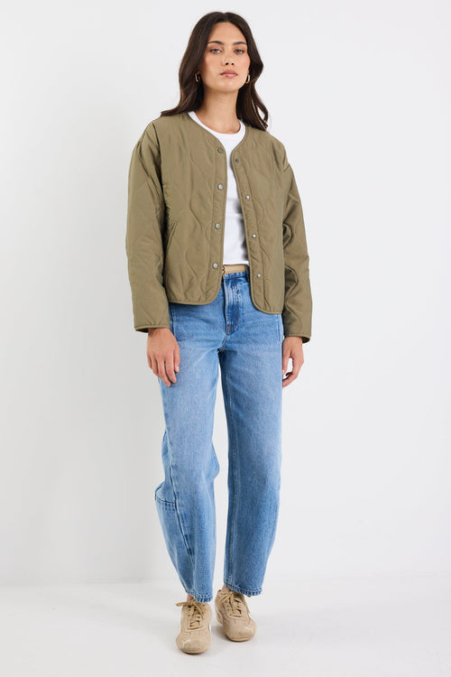 Woman wearing a green jacket and blue jeans on a white background