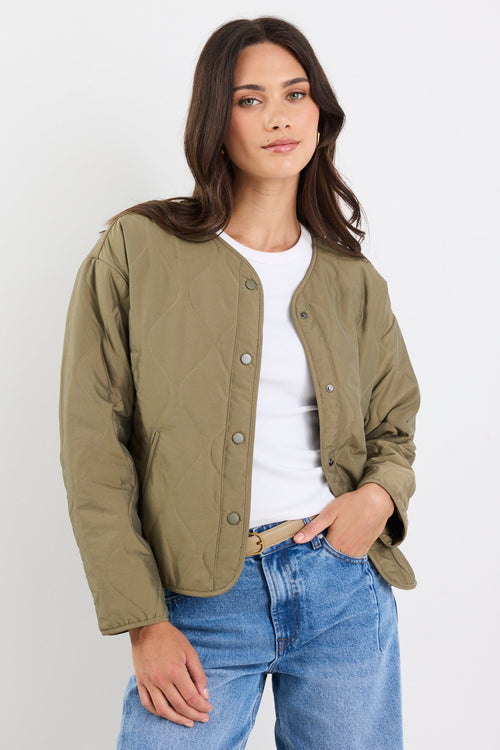 Woman wearing a green jacket and blue jeans against a white background