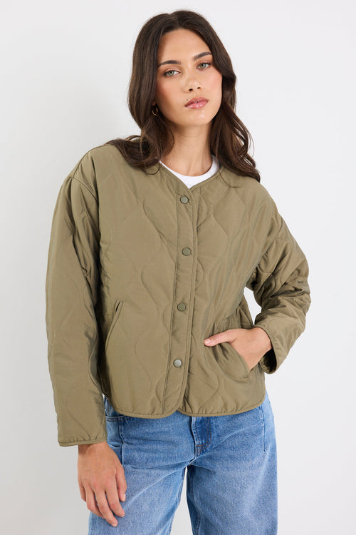 Woman wearing a green jacket and blue jeans on a white background