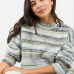 Woman wearing a striped sweater sitting on a white surface