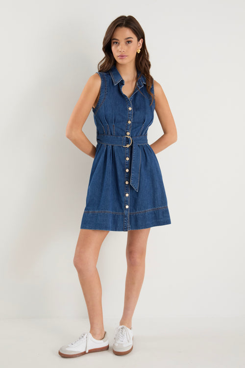 the model wears a blue denim mini dress with white sneakers