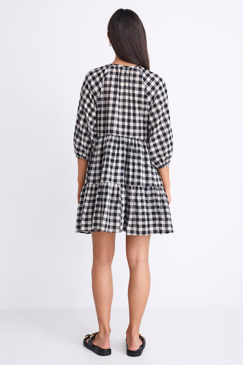 Person wearing a black and white checkered dress on a white background