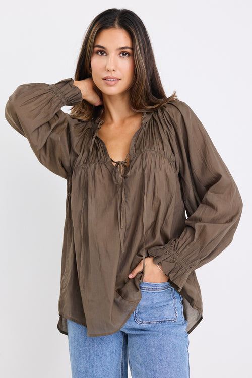 model wears a olive blouse with light blue jeans