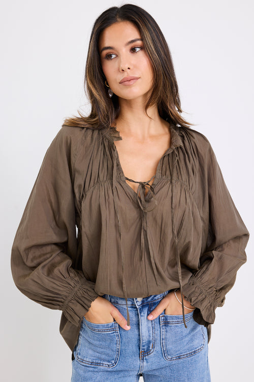 model wears a olive blouse with light blue jeans