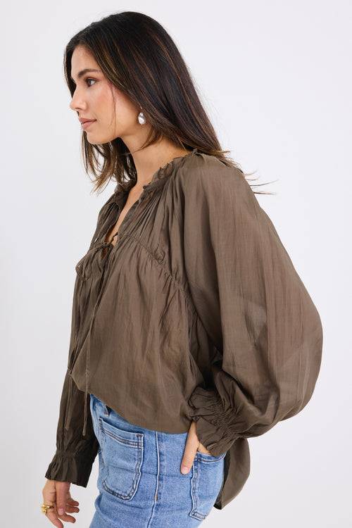 model wears a olive blouse with light blue jeans