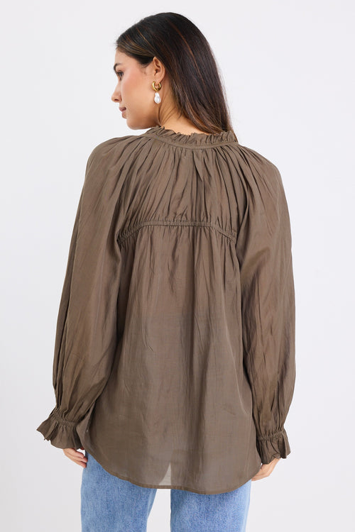 model wears a olive blouse with light blue jeans