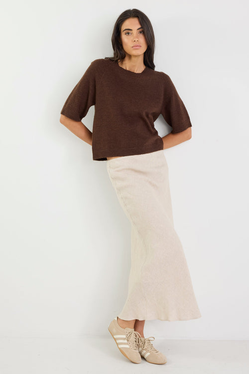 Woman wearing a brown top and beige skirt on a white background