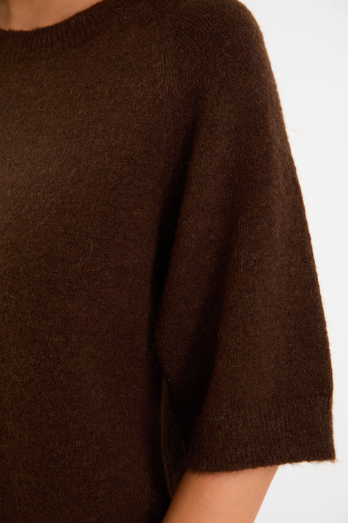 Woman wears a chocolate knit tee and blue jeans with brown loafers