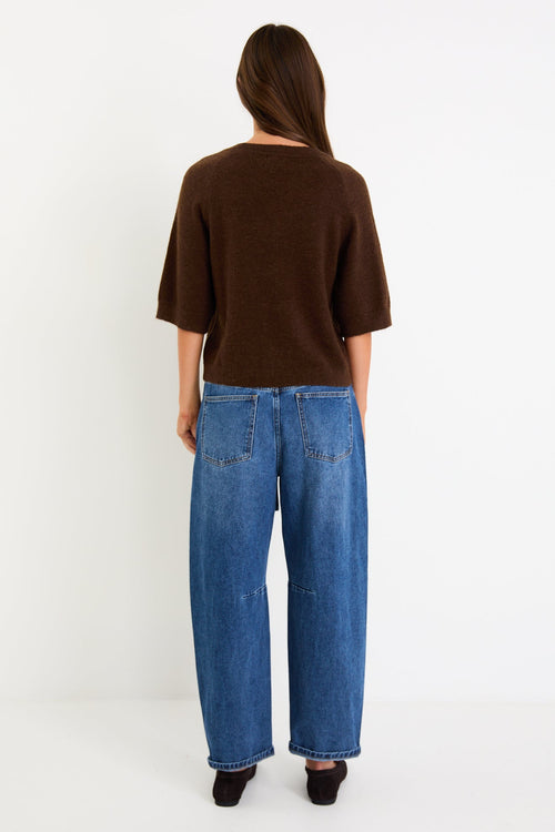 Woman wears a chocolate knit tee and blue jeans with brown loafers