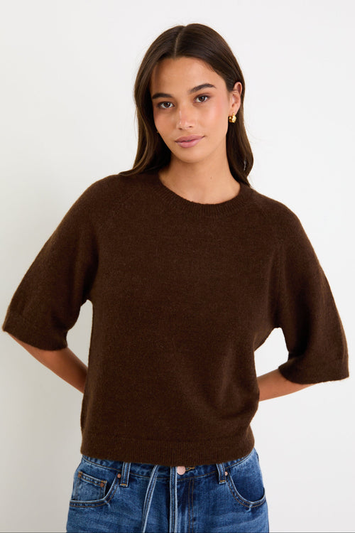 Woman wears a chocolate knit tee and blue jeans with brown loafers