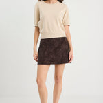 Woman wearing a beige sweater and brown skirt on a white background