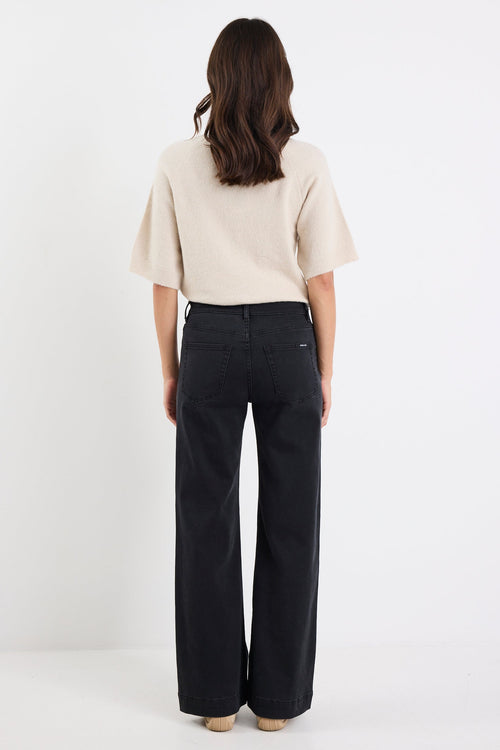 Person wearing a beige top and black pants on a white background