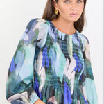 Woman wearing a colorful floral blouse against a white background